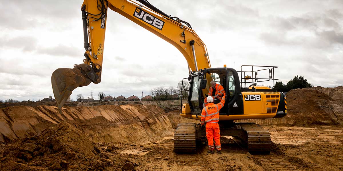 A JCB digger excavating material from a site